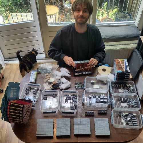 Cacklin Slayers' Josha packing initiative tracker sets at the table. A fat cat is visible in the background.