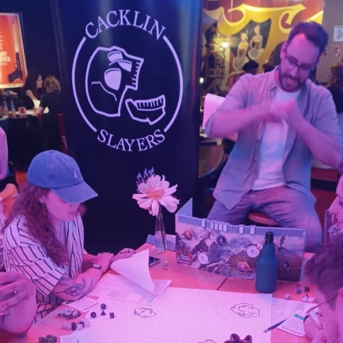 Marco DMing our level 3 seafaring one-shot at Cinerama Rotterdam. He has an initiative tracker on his DM screen. Behind him stands a black banner with the logo of Cacklin Slayers on it.